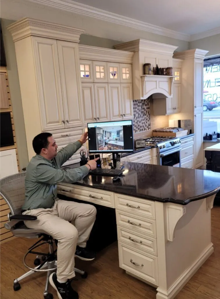 A man sitting at his computer desk in the kitchen.